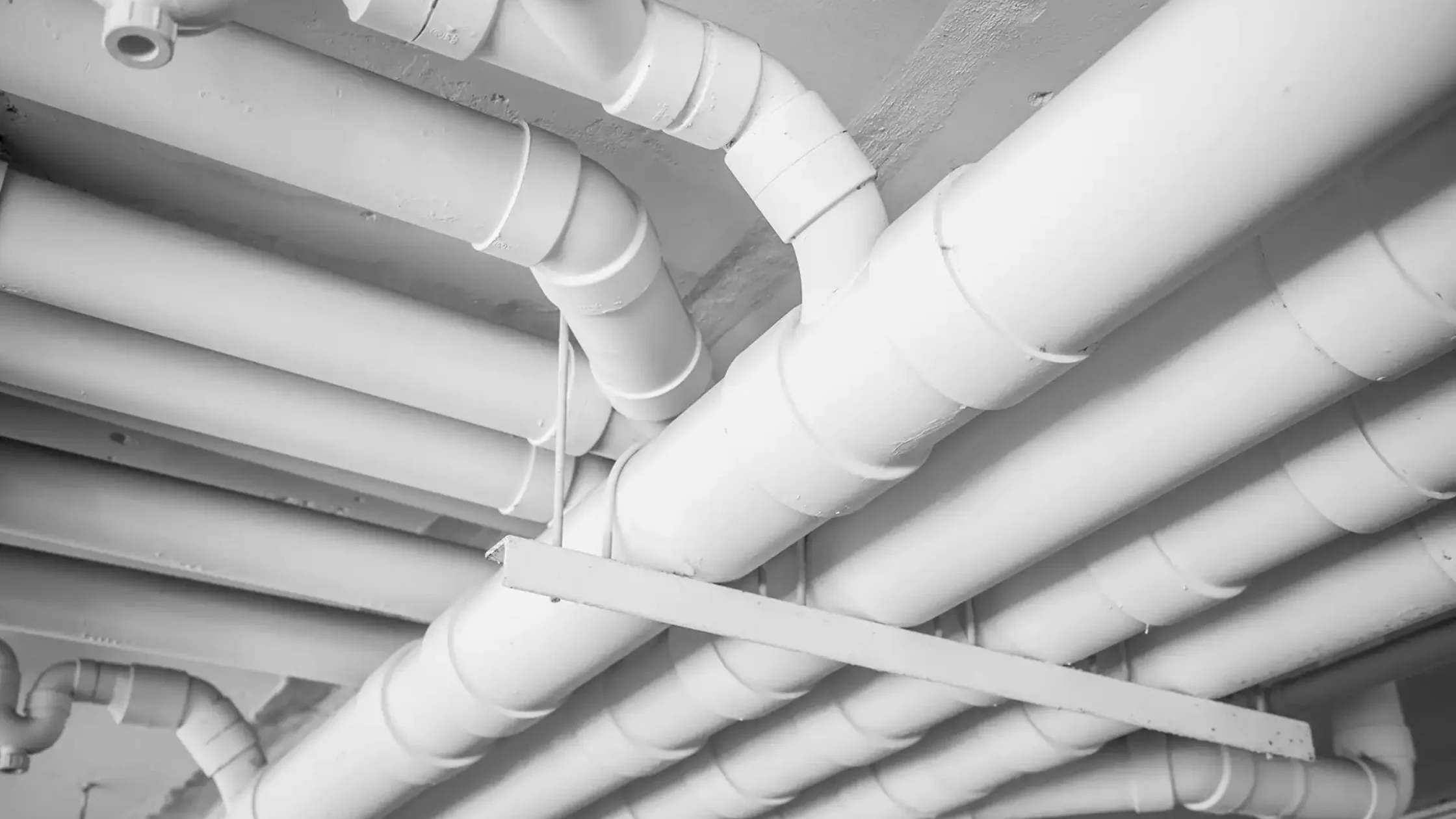  Ceiling with a network of painted white plumbing pipes.